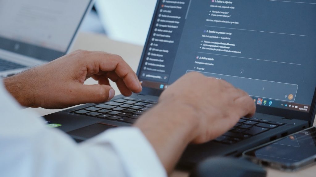 Mãos a escrever num portátil com um assistente de inteligência artificial no ecrã